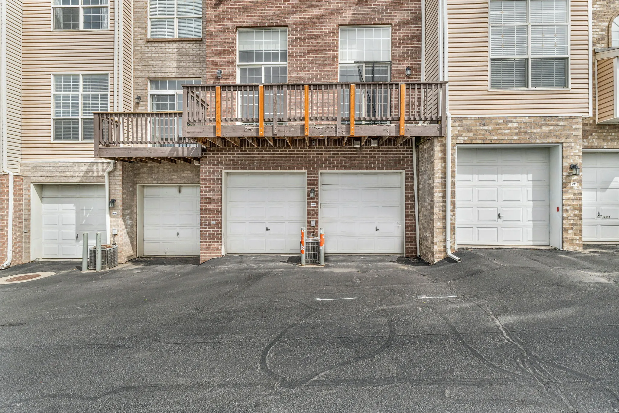 Brick and siding exterior featuring multiple white panel garage doors