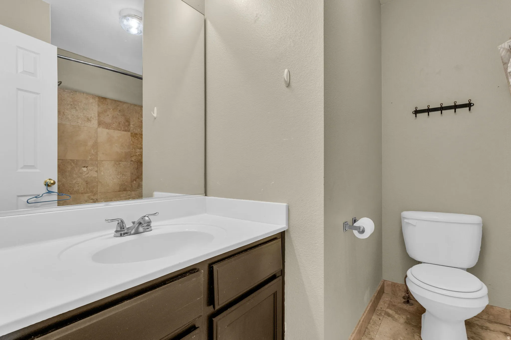 Bathroom vanity featuring an integrated sink with chrome fixtures, a full-width mirror, and dark wood-finish cabinetry