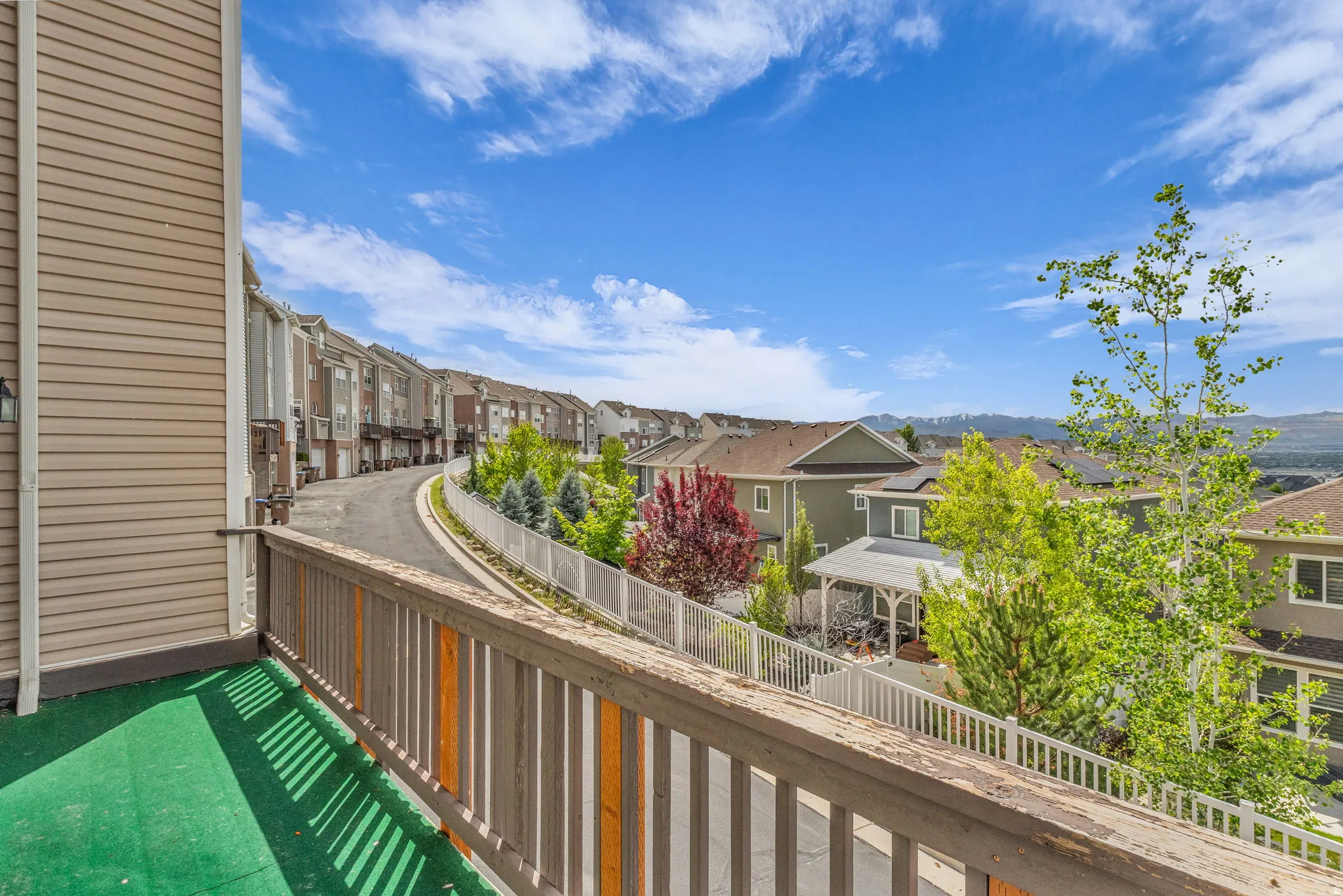 Outdoor balcony featuring a wooden railing and green artificial turf