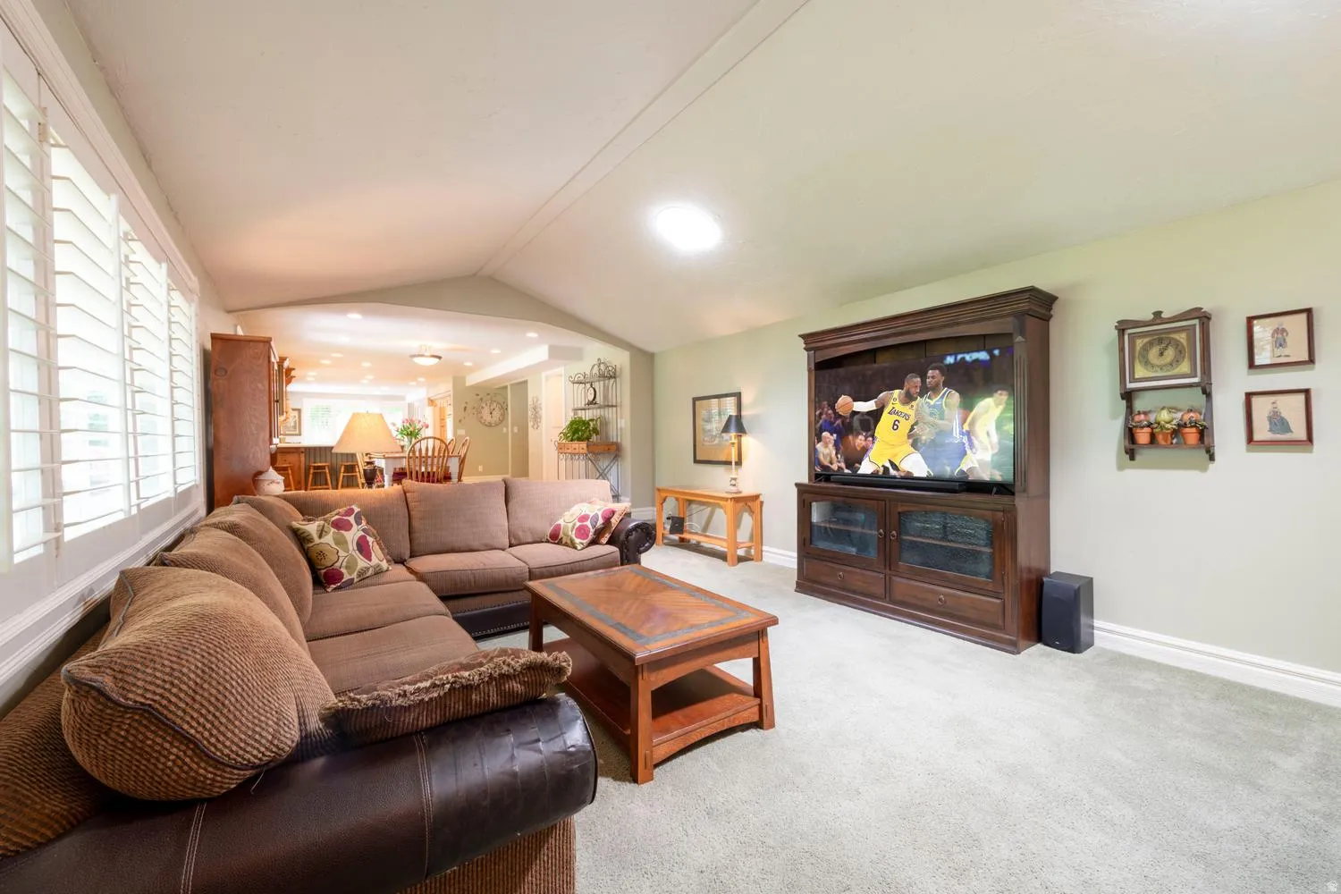 Living space featuring plush carpet, vaulted ceiling, and recessed lighting