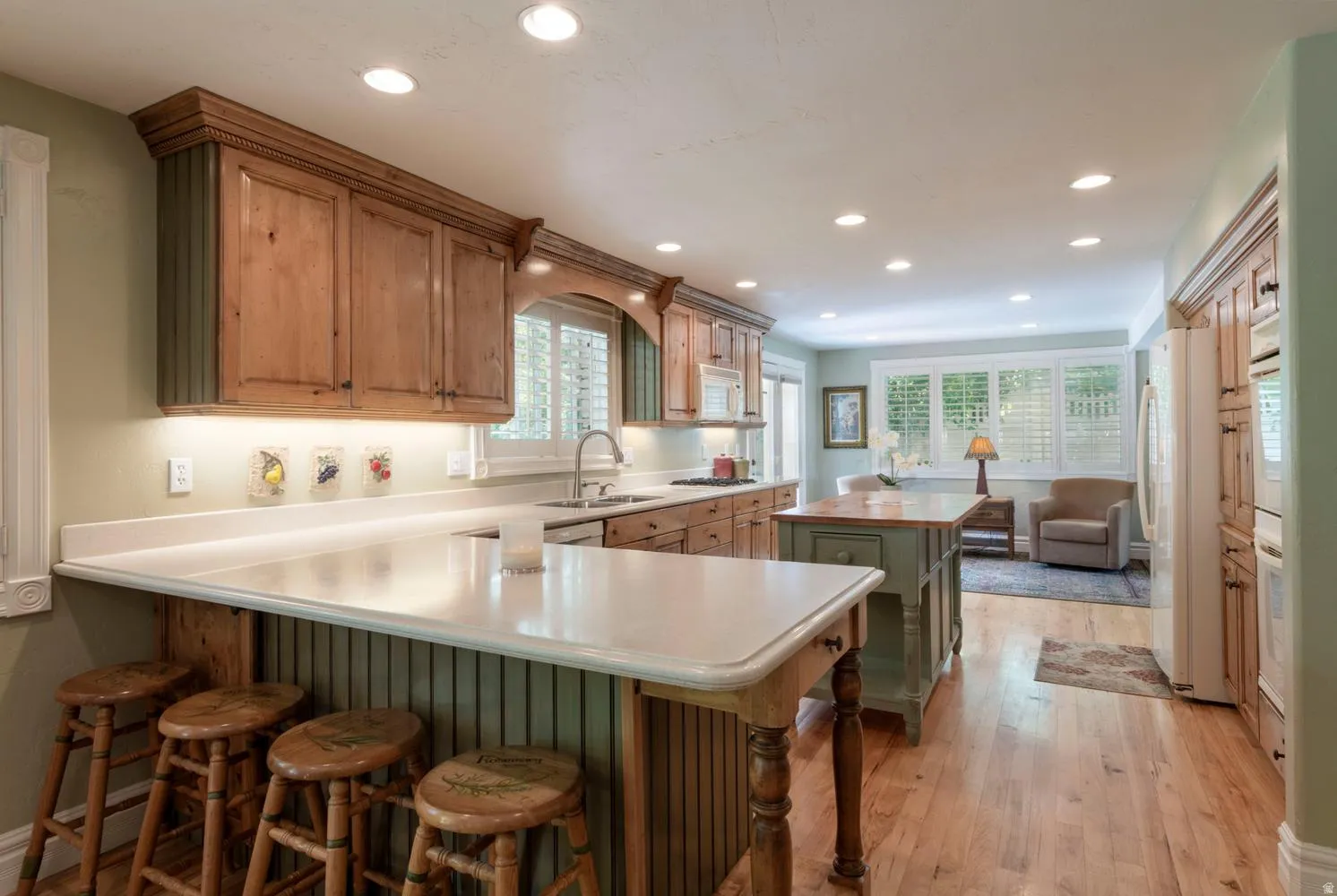 Kitchen featuring wood-finish cabinetry, recessed lighting, and a white countertop breakfast bar