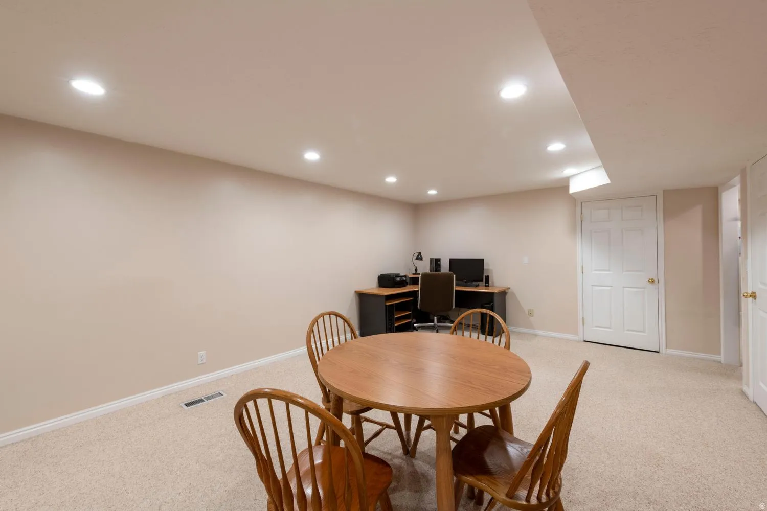 Finished lower level featuring recessed lighting, neutral wall paint, and light-toned carpet flooring