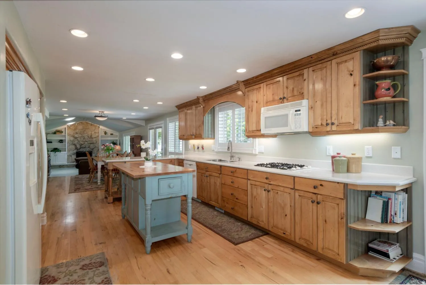 Expansive kitchen featuring wood-finish flooring, light wood cabinetry with built-in corner shelving, and recessed lighting