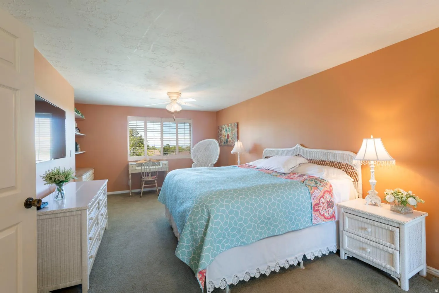 Carpeted room with a ceiling fan, window with horizontal blinds, and a built-in wall-mounted television