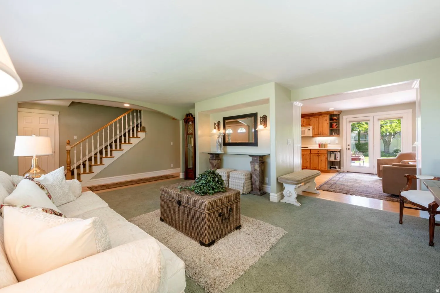 Spacious interior featuring light green wall paint, a carpeted living area, and a bright kitchen beyond