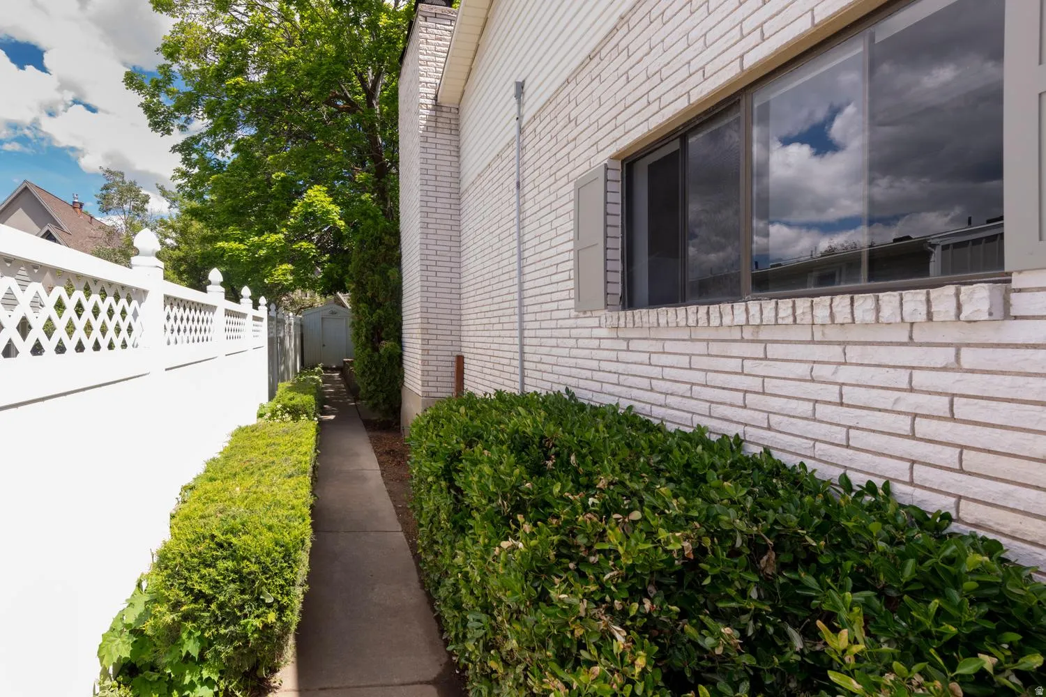 White brick exterior with a large picture window, flanked by decorative shutters