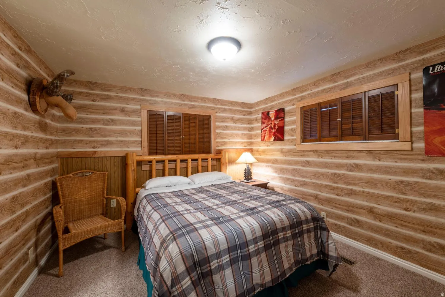 Interior space featuring textured wood-finish wall paneling, a wood-frame window with dark wood shutters, and neutral carpet flooring