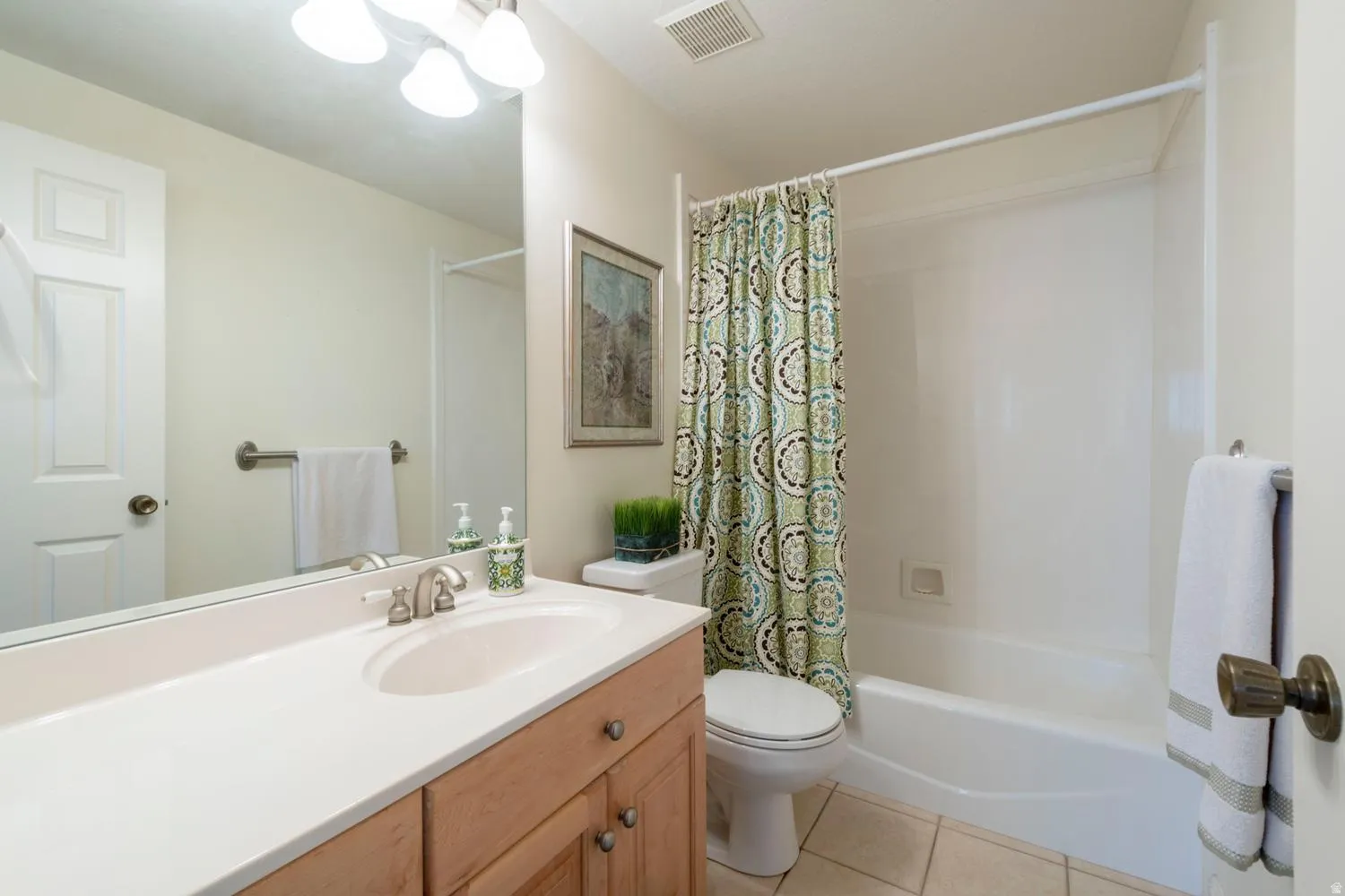 Bathroom featuring a light wood-finish vanity with an integrated sink and brushed nickel faucet
