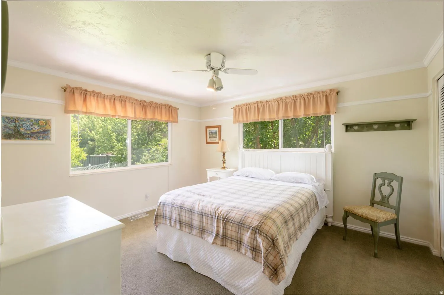 Room featuring two windows, crown molding, a ceiling fan with light fixture, and textured carpeting