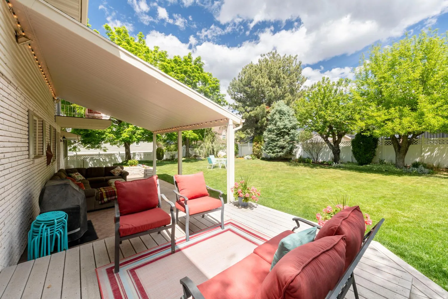 Expansive grassy backyard featuring mature trees and a privacy fence