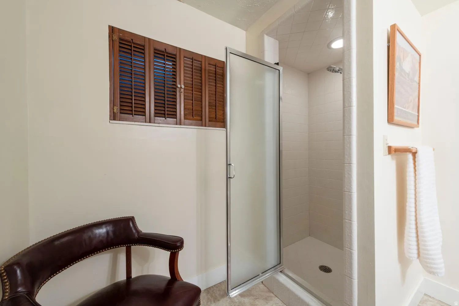 Shower enclosure with a frosted glass door, tiled walls, and a recessed ceiling light