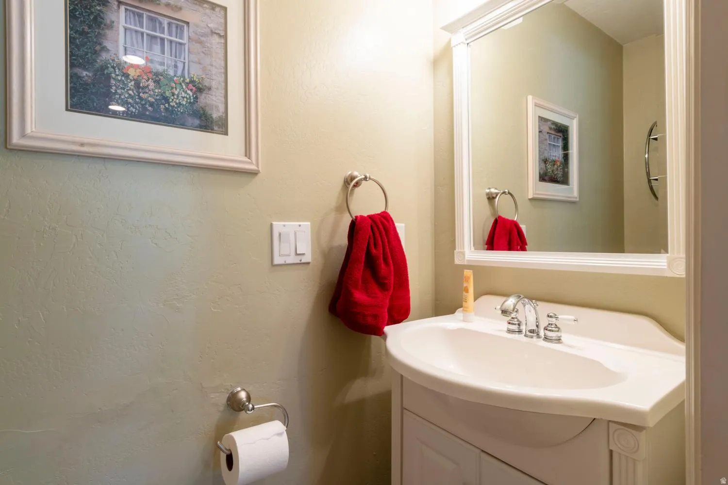 Bathroom vanity featuring a white ceramic sink with chrome fixtures and a framed mirror