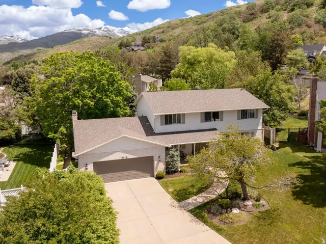 Traditional two-story residence featuring a two-car garage, mature landscaping, and a covered front porch