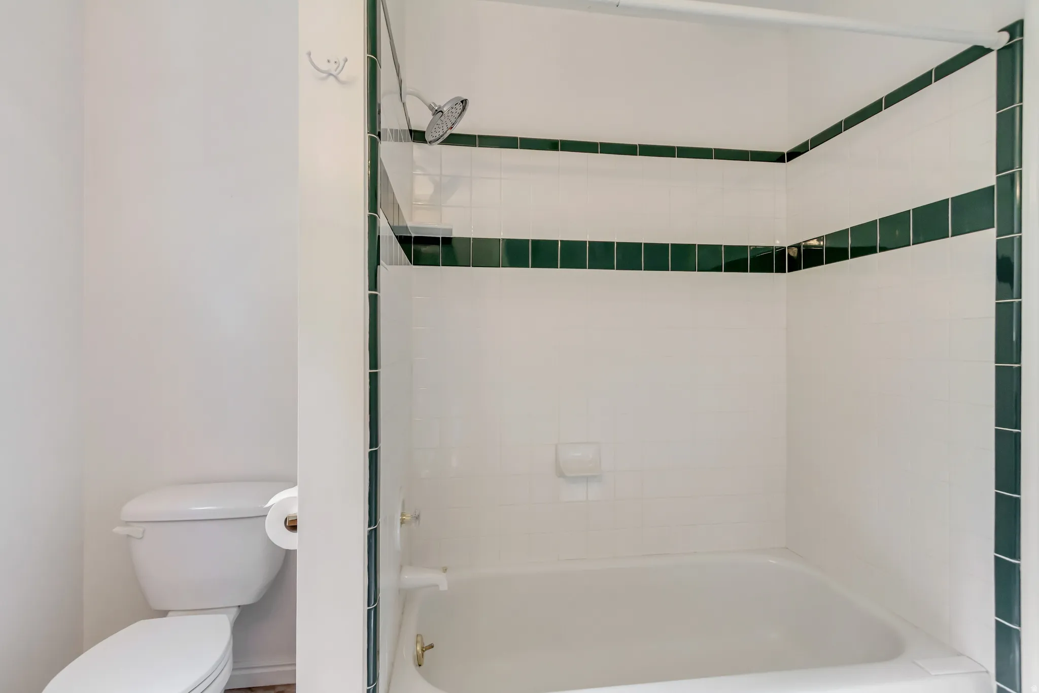 Tub and shower combination with white tile surround and dark green accent bands