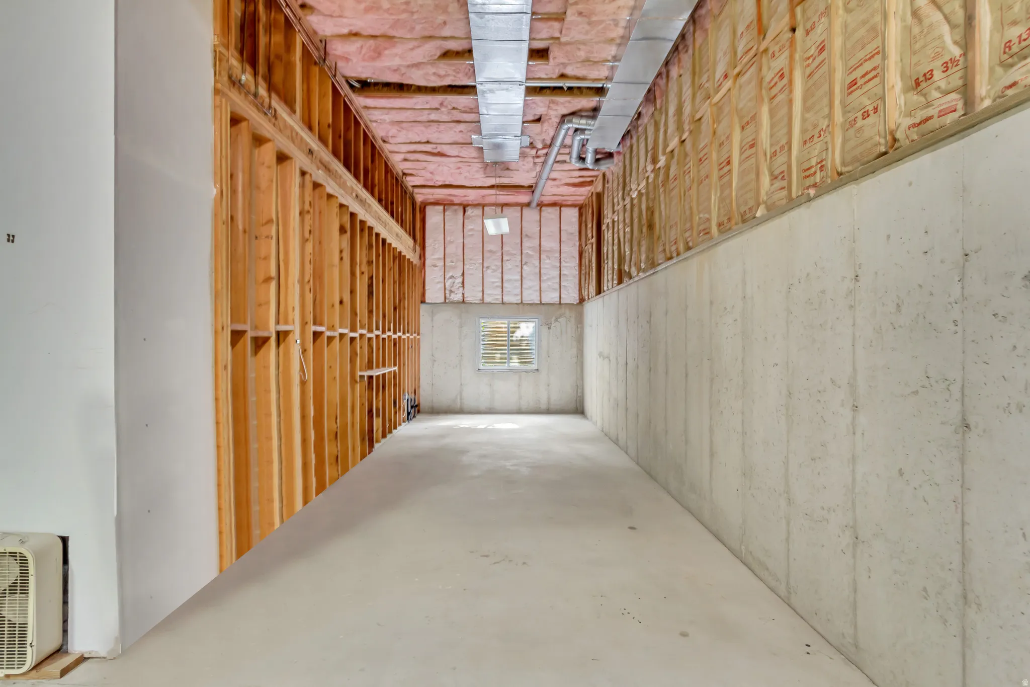 Unfinished basement featuring exposed framing, batt insulation, concrete walls, and concrete flooring