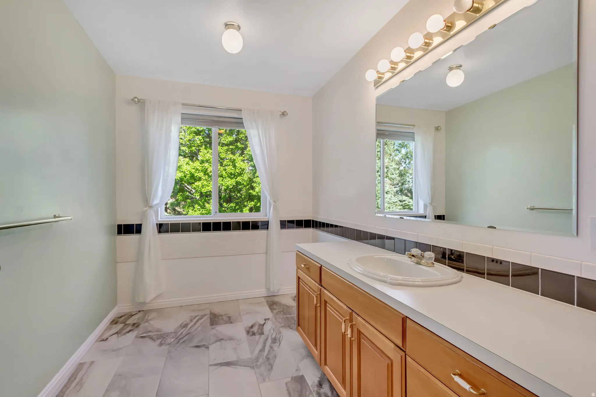 Bathroom featuring a large vanity with wood cabinetry, a white countertop, and an integrated sink