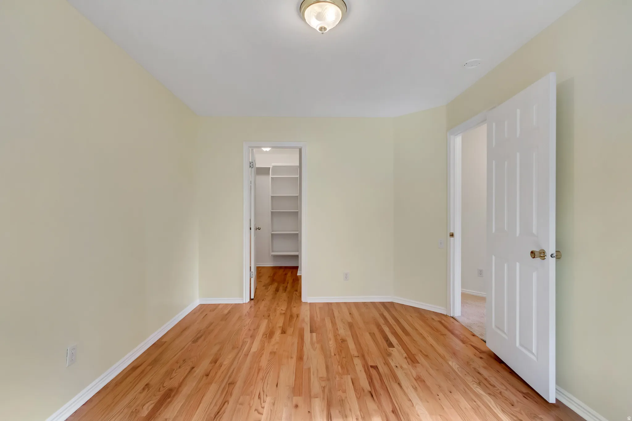 Light-filled room featuring wood-finish flooring, neutral wall tones, white baseboards, and a ceiling-mounted light fixture