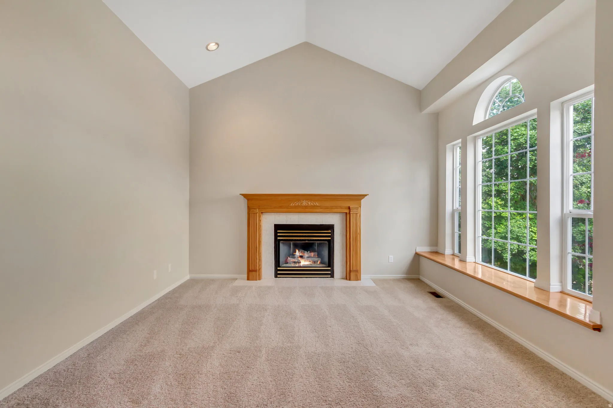 Living area featuring a vaulted ceiling and an integrated gas fireplace with a wood mantel