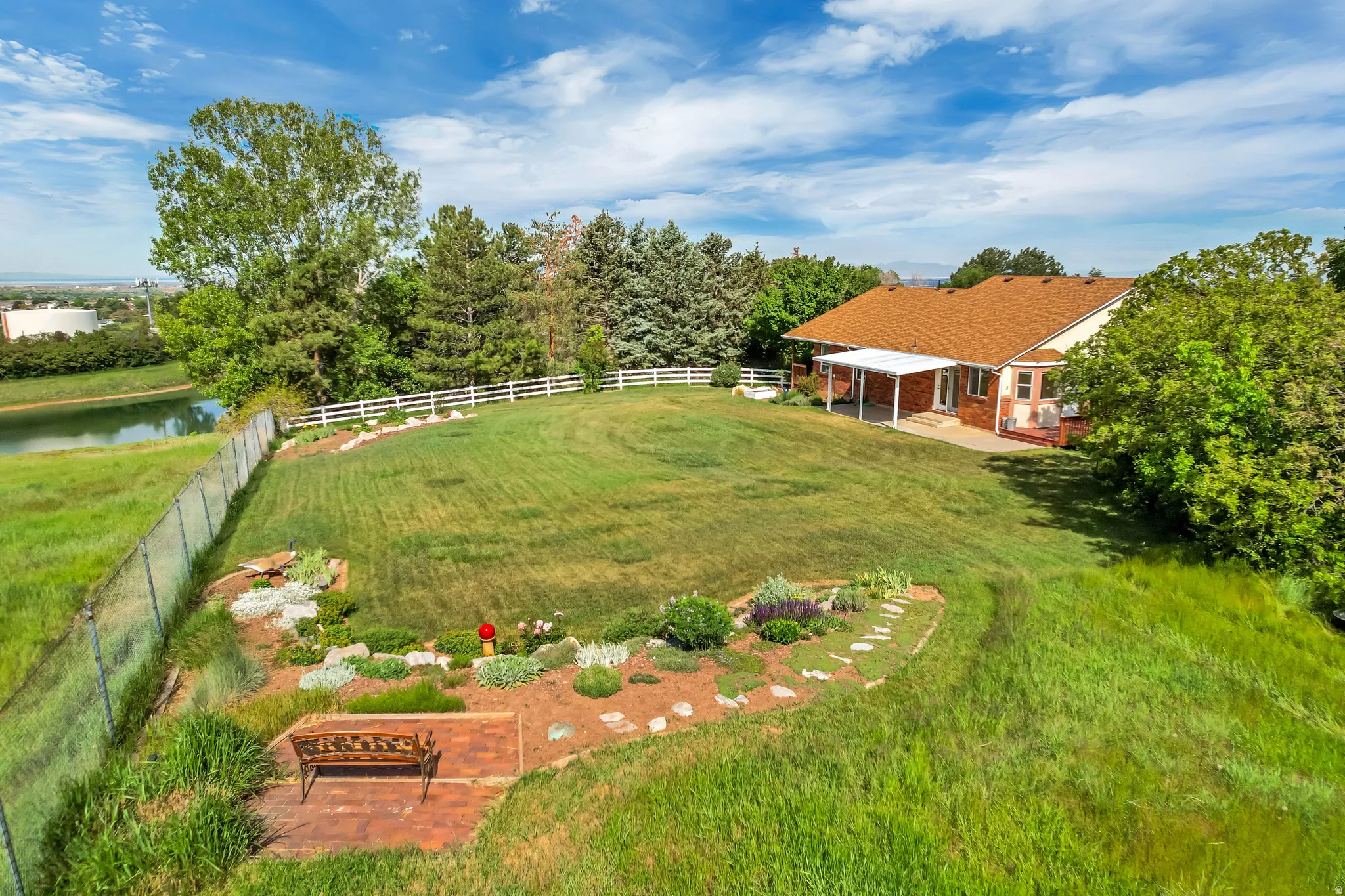 Expansive sloped lawn with mature trees and a white picket fence