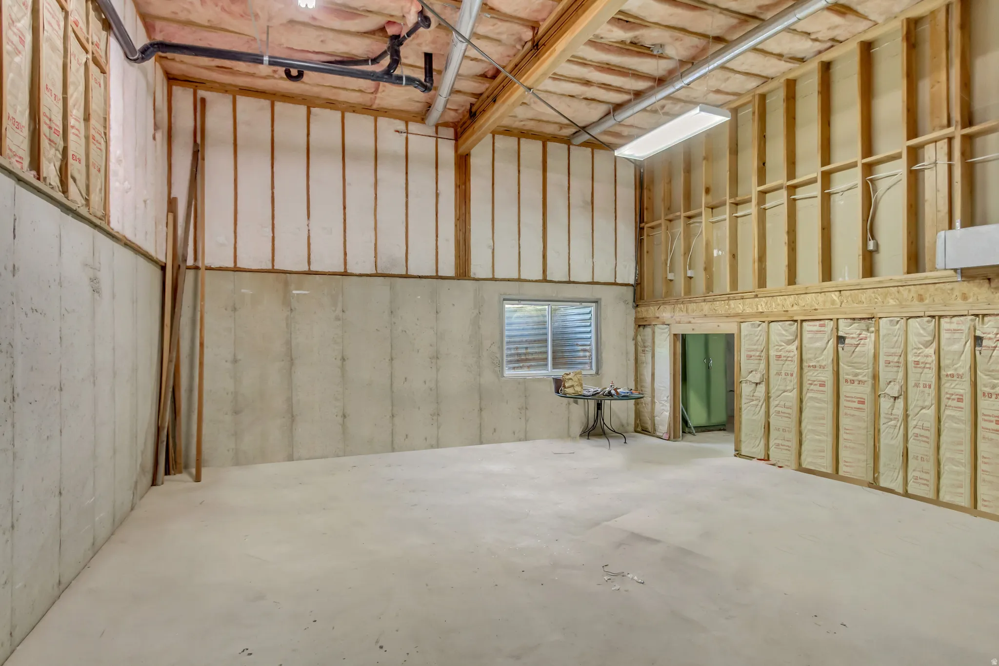 Unfinished open-concept space featuring exposed wood framing, concrete foundation walls, and a concrete floor