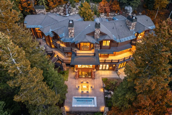 Stone and wood-clad exterior with multiple balconies, an outdoor fireplace, and an integrated hot tub