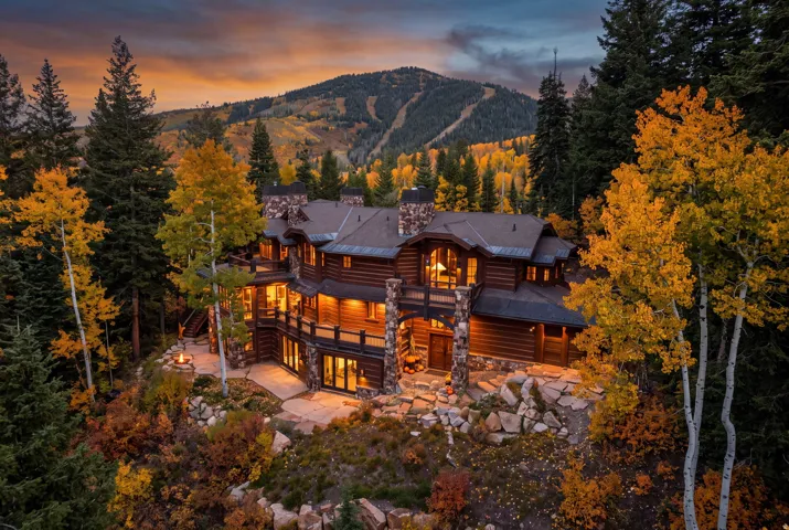Log-sided residence with multiple stone chimneys, expansive outdoor patios, and a built-in fire pit