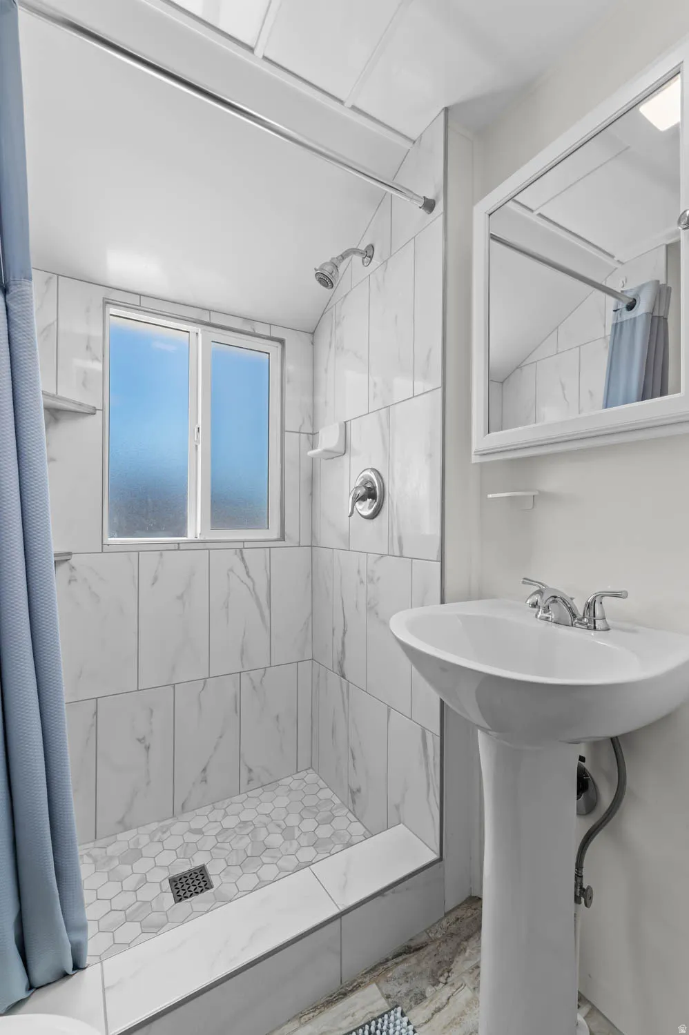 Pedestal sink with chrome faucet, complemented by a framed mirror