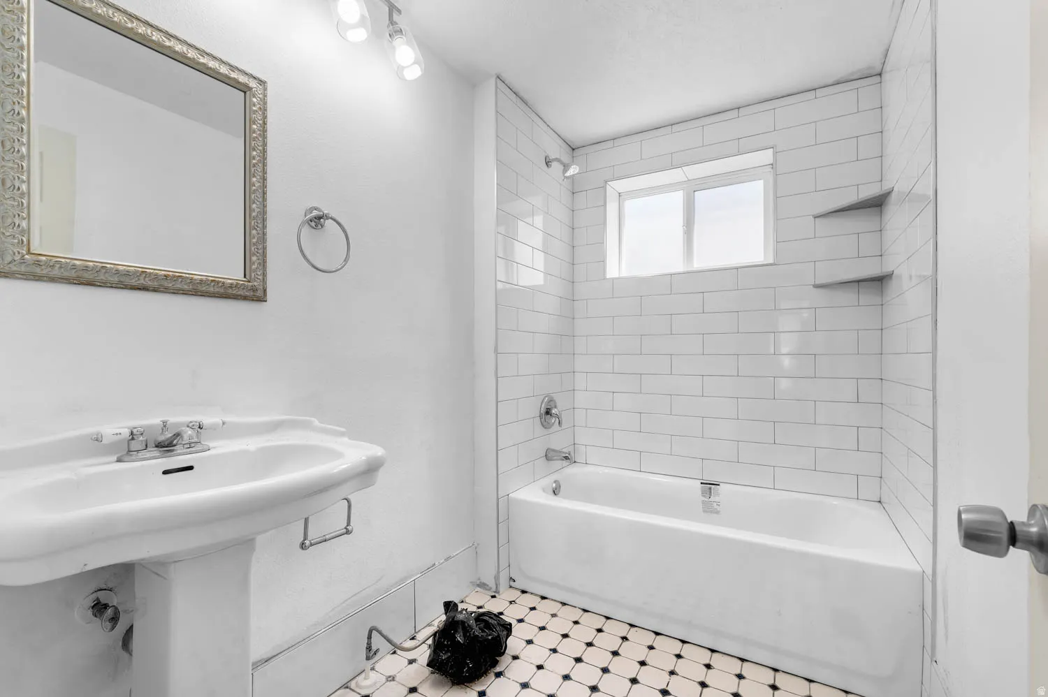 Bathroom featuring a pedestal sink, framed mirror, and a classic black and white tiled floor