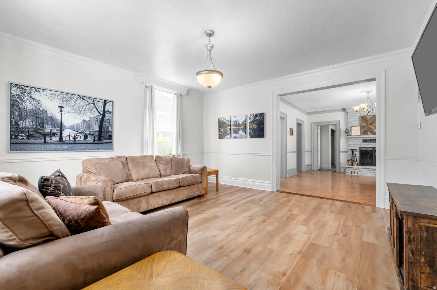 Spacious reception room featuring wood-finish flooring, white walls with wainscoting, and crown molding