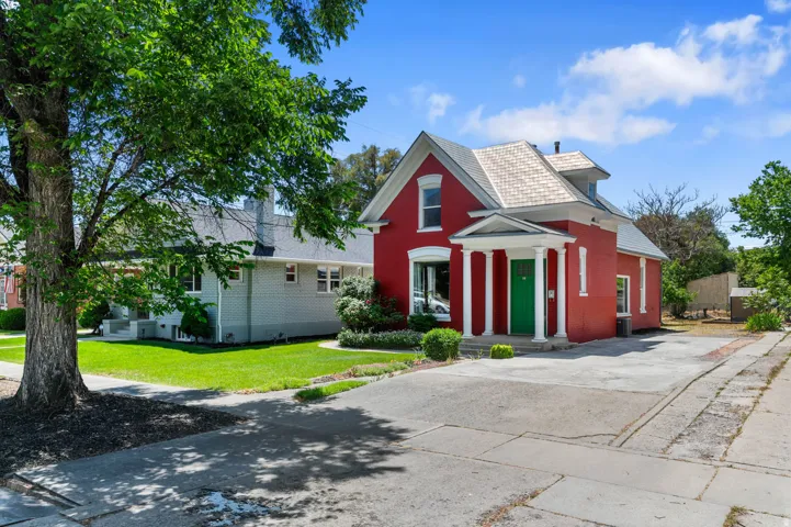 Red brick exterior with white trim, a green entrance door, and a covered porch with white columns