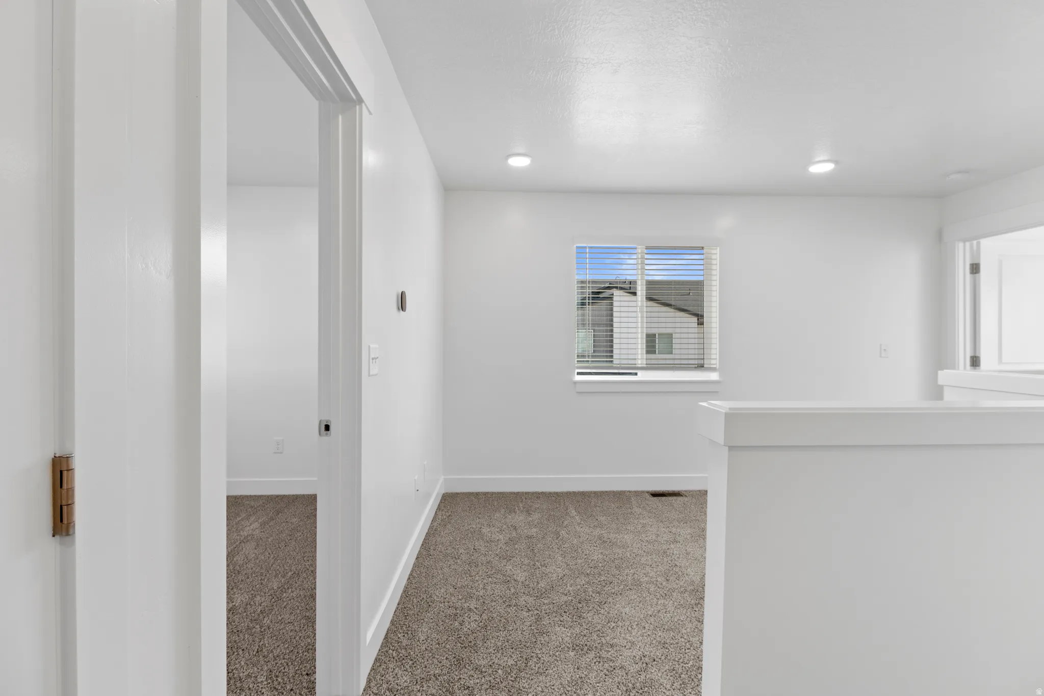 Light-filled interior space featuring neutral carpeting and white wall finishes