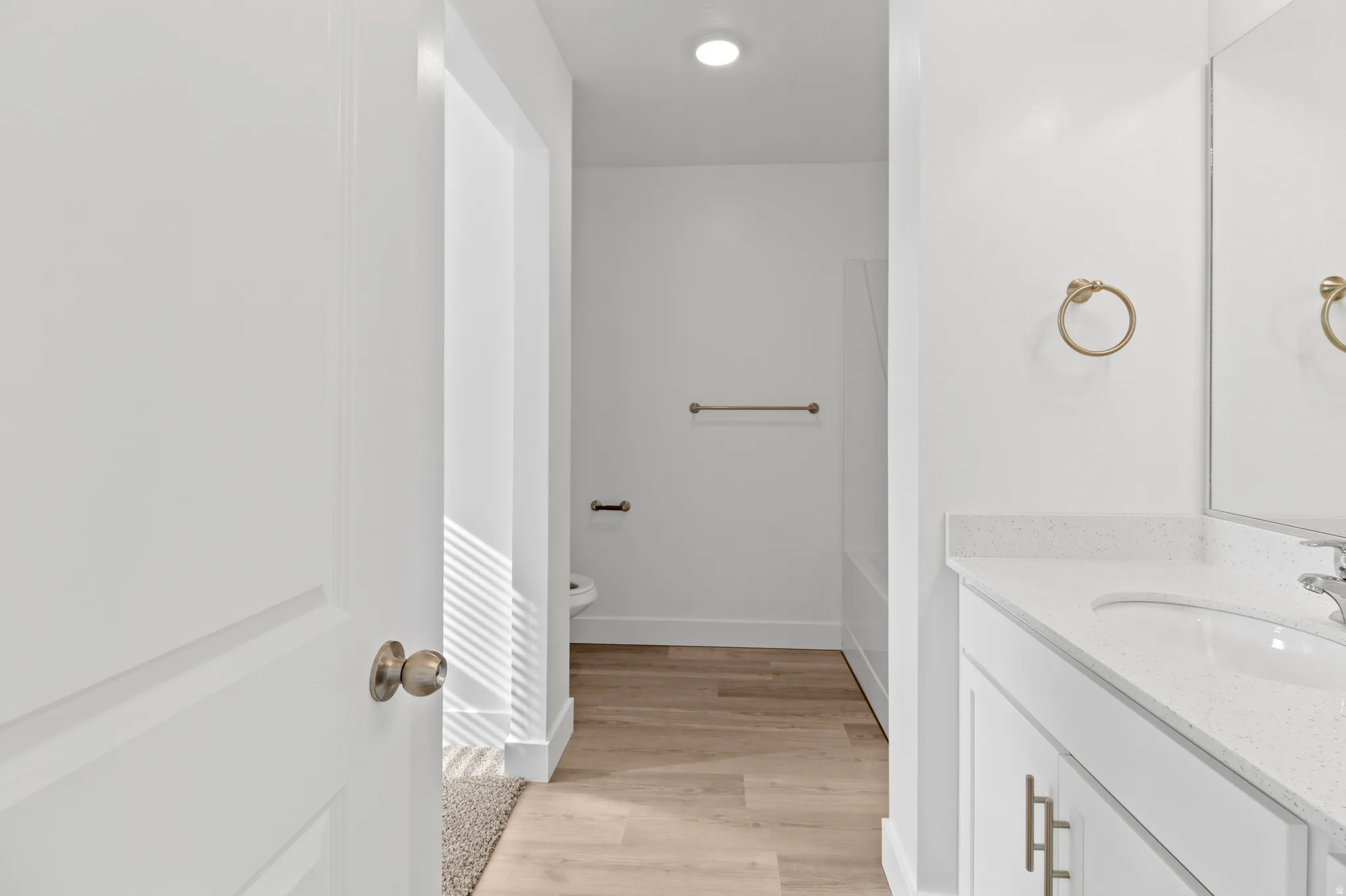 Bathroom vanity featuring a white countertop with integrated sink, brushed brass hardware, and a large mirror