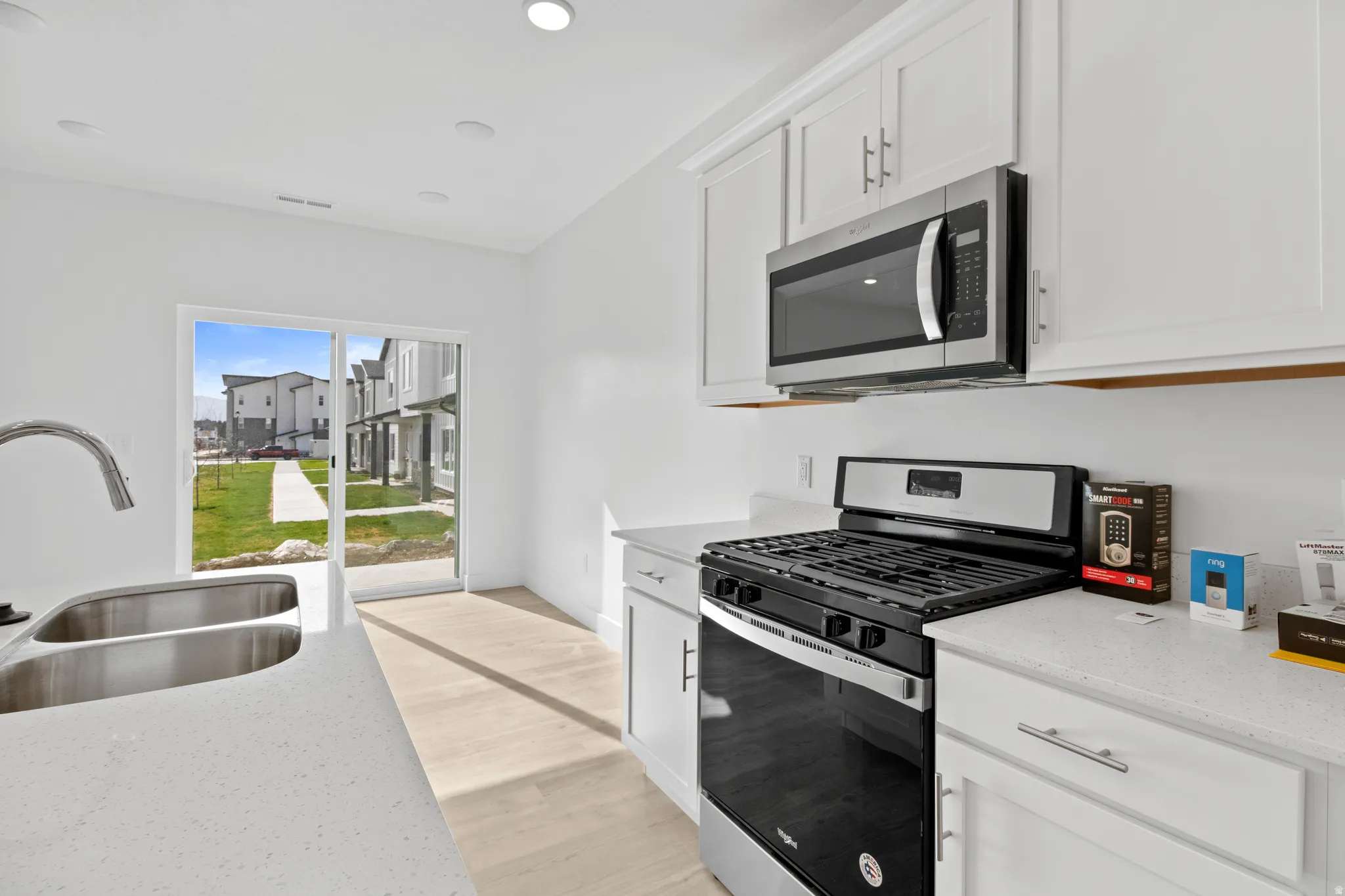 Modern kitchen featuring white cabinetry, light-toned countertops, and stainless steel appliances including a gas range and microwave
