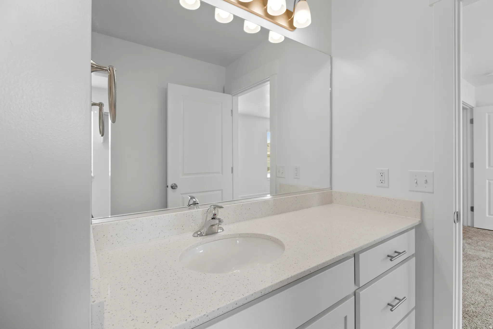 Modern bathroom vanity featuring a light speckled countertop, integrated sink, and brushed nickel faucet