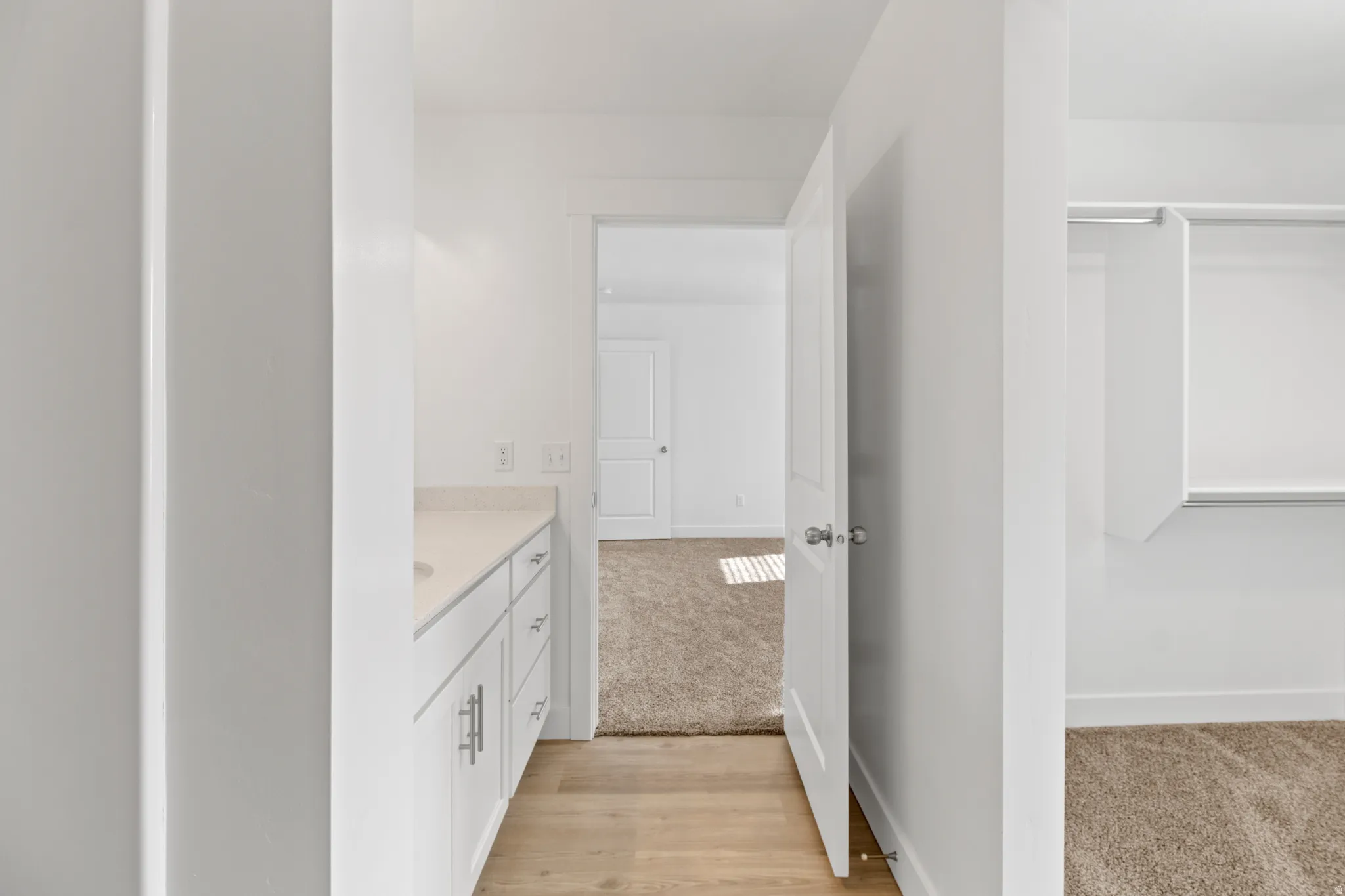 Vanity area featuring a quartz countertop, white cabinetry with brushed nickel hardware, and wood-finish flooring