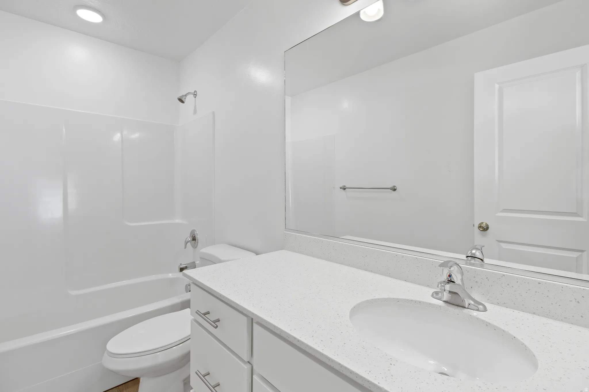 Bathroom featuring a white vanity with an integrated sink, polished chrome faucet, and a large mirror
