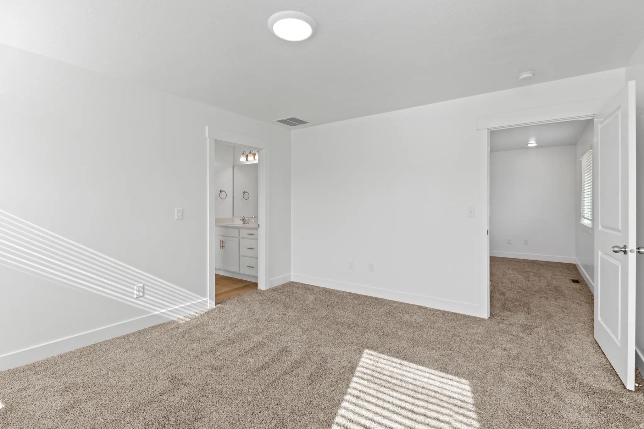 Spacious room featuring neutral carpeting, a modern recessed ceiling light, and white baseboards