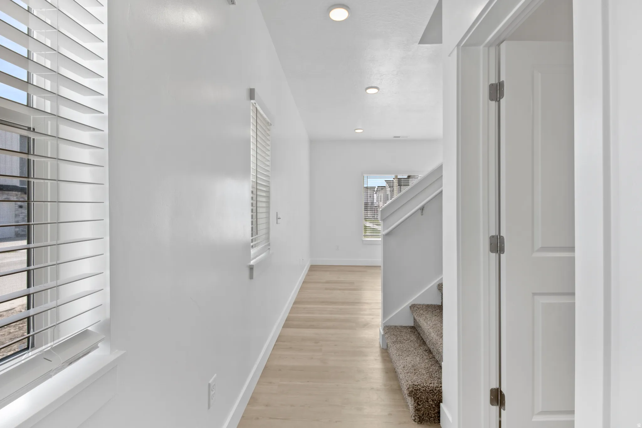 Hallway featuring wood-finish flooring, recessed lighting, and white walls