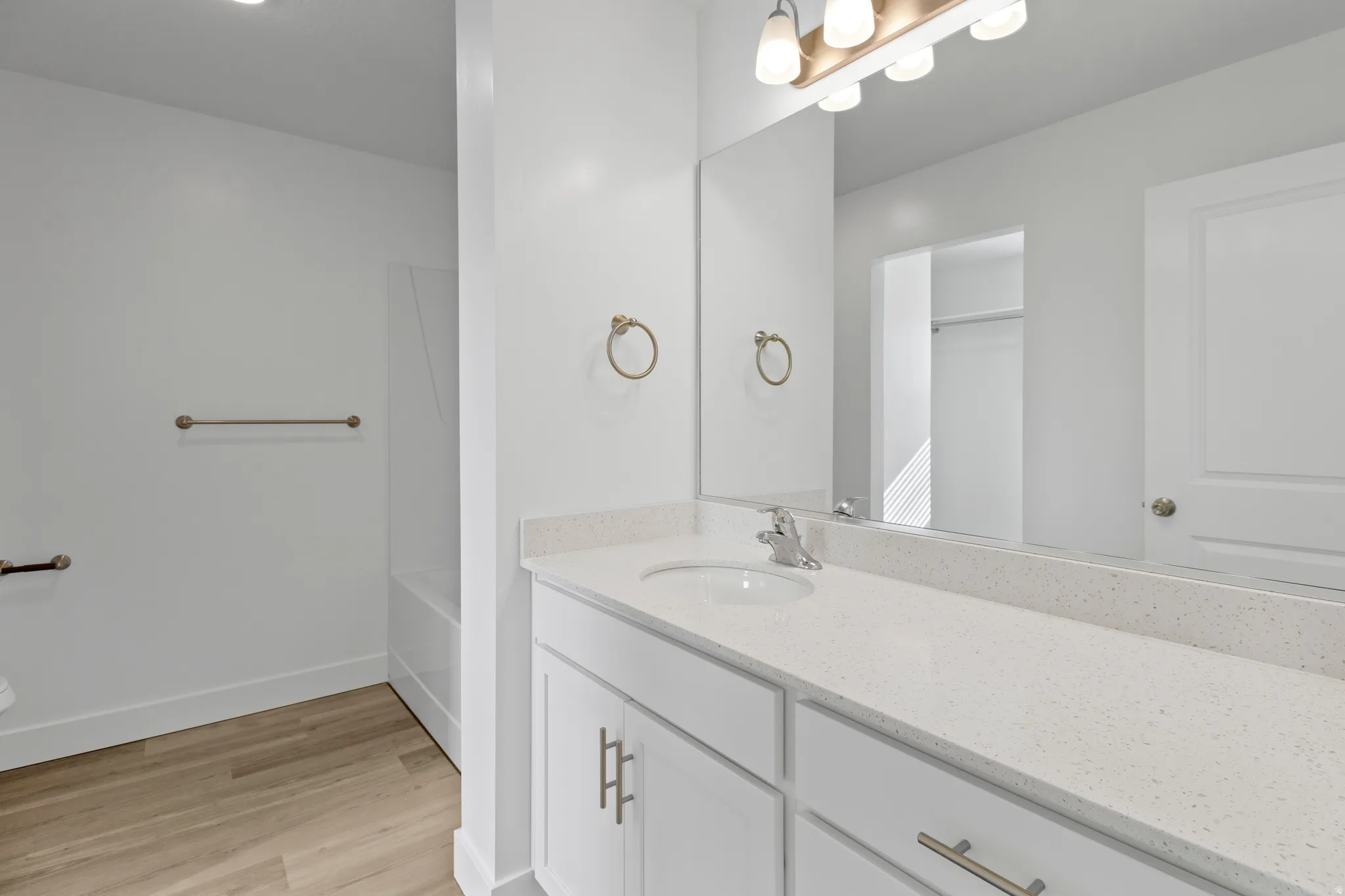Bathroom featuring a single vanity with a white countertop and undermount sink, brushed nickel faucet, and white cabinetry with brushed nickel hardware