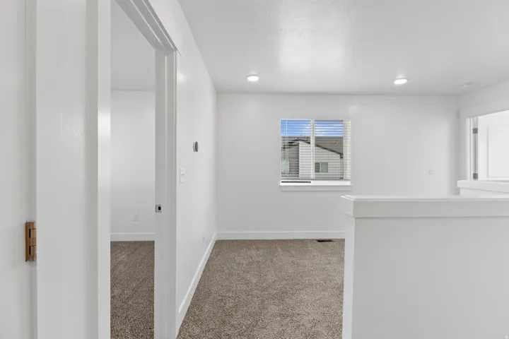 Light-filled interior space featuring neutral carpeting and white wall finishes
