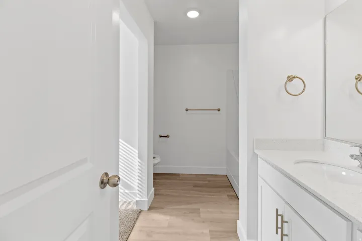 Bathroom vanity featuring a white countertop with integrated sink, brushed brass hardware, and a large mirror