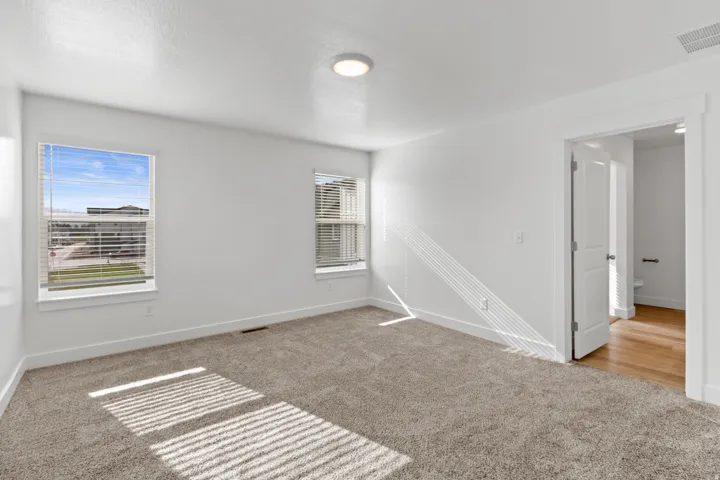 Carpeted room featuring dual windows with blinds, a flush mount ceiling light, and white trim