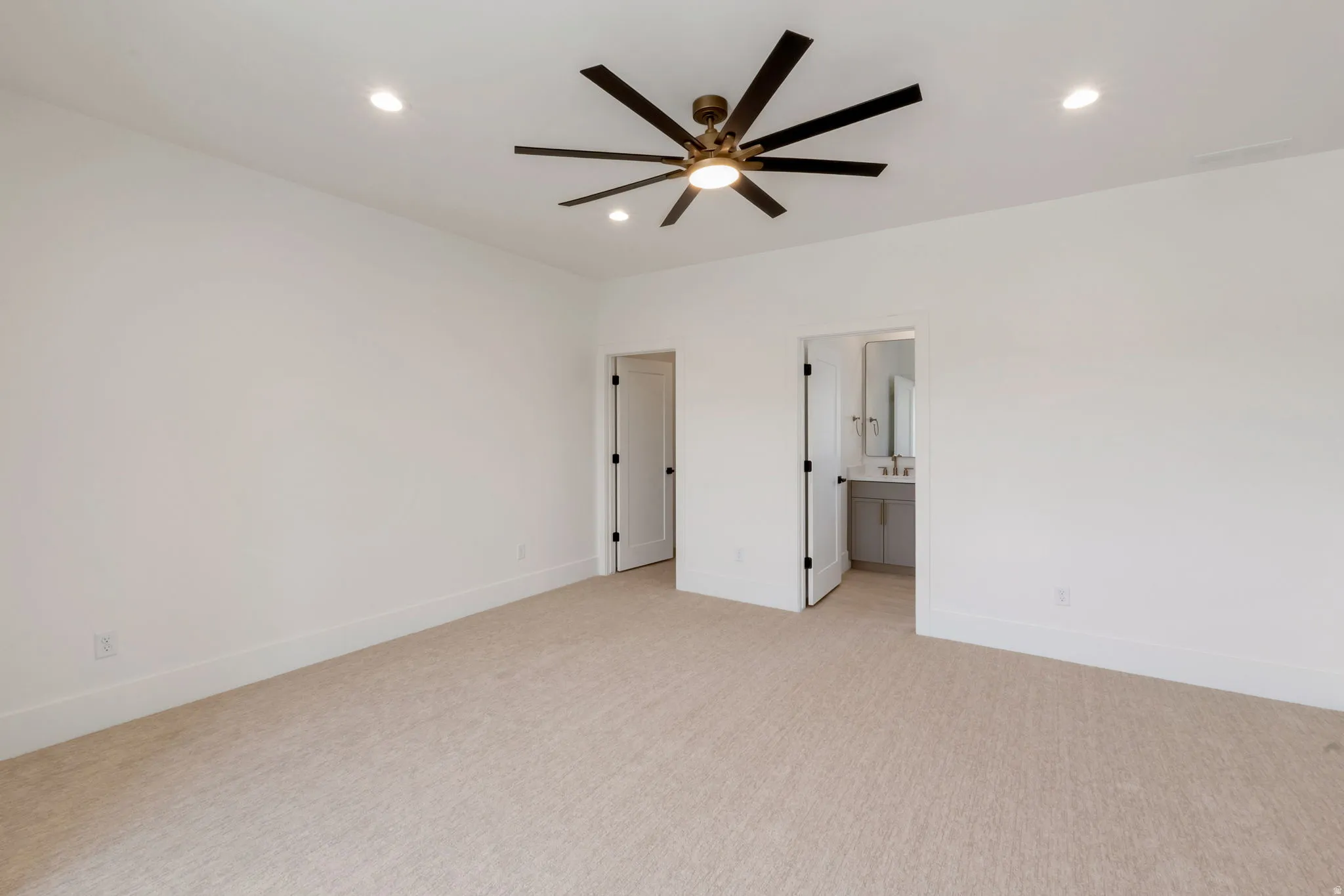 Spacious room featuring neutral carpeting, recessed lighting, and a contemporary ceiling fan with a bronze finish