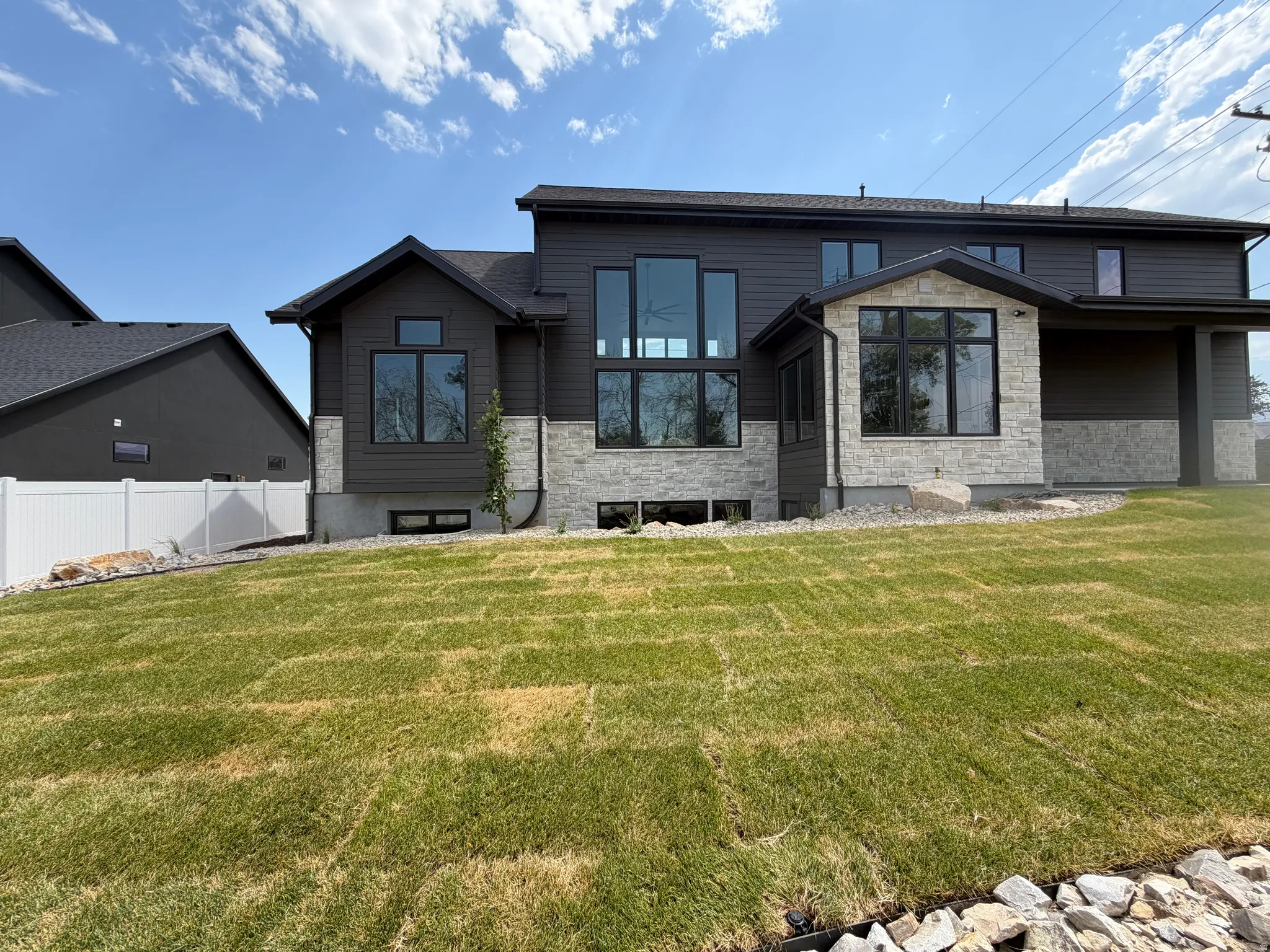 Modern exterior featuring dark gray siding and light-toned stone accents