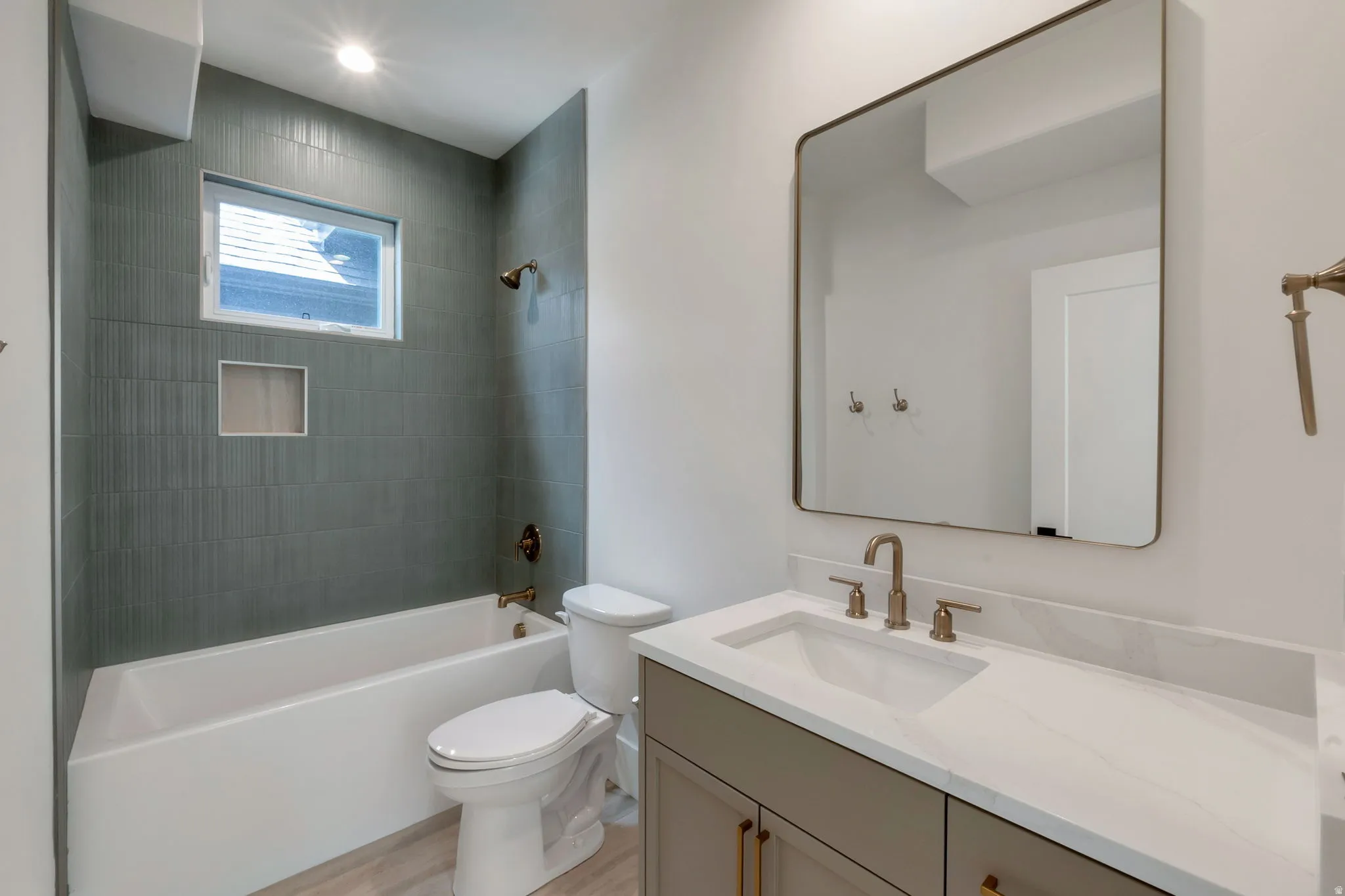 Bathroom featuring a tub/shower combination with green vertically-stacked tile, a built-in shower niche, and a window for natural light