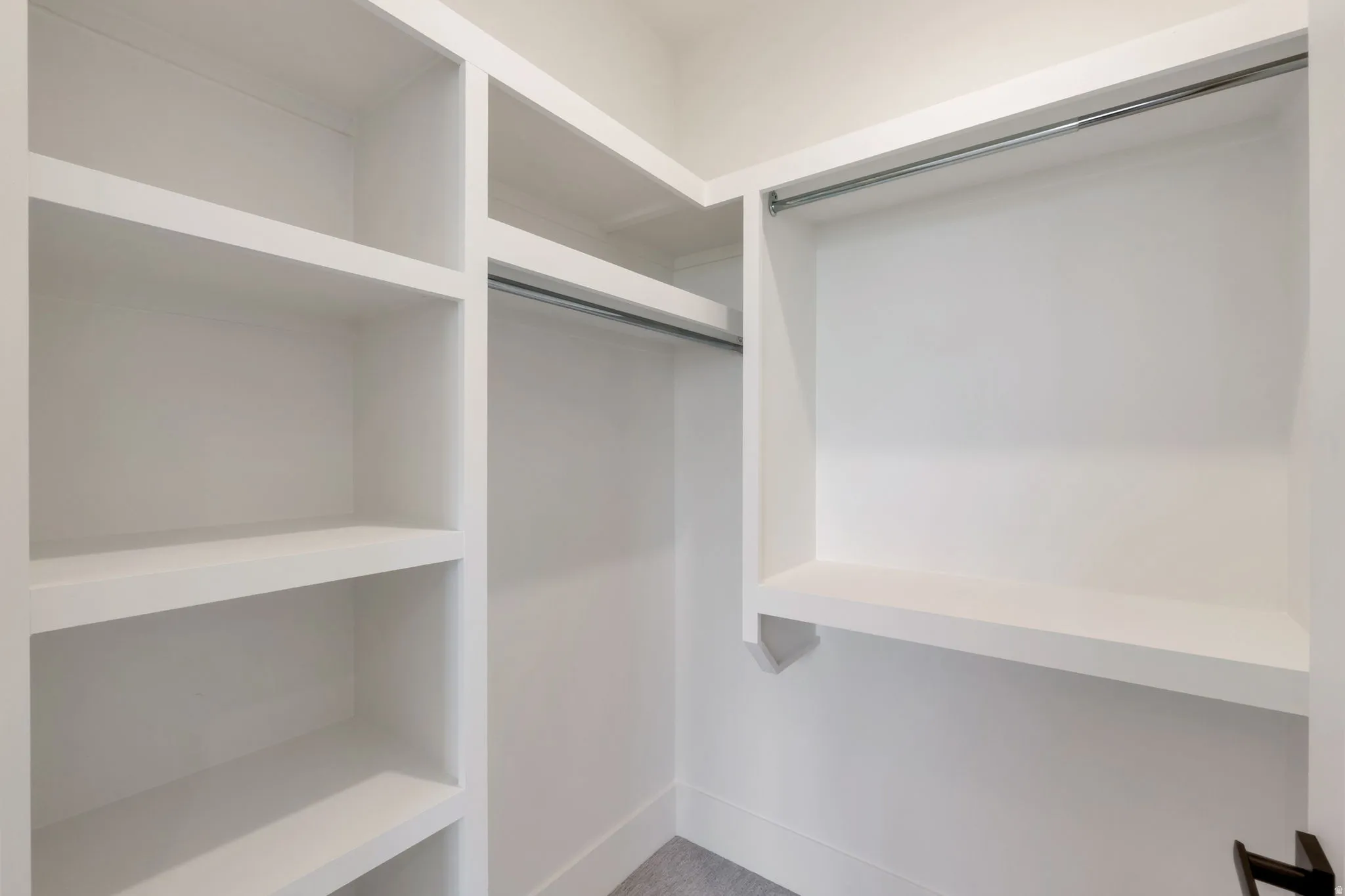 Walk-in closet featuring white built-in shelving, multiple hanging rods, and light-toned flooring