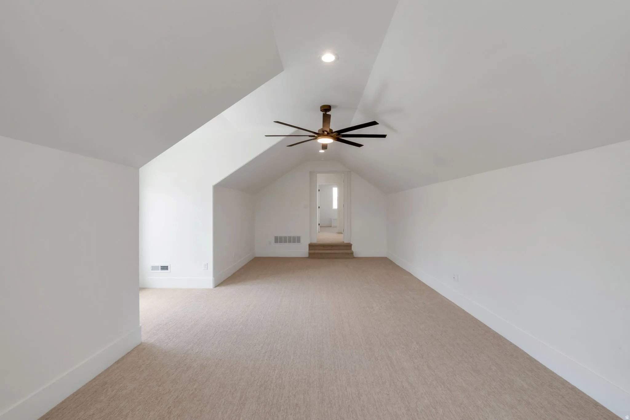 Spacious room featuring vaulted ceilings, a contemporary ceiling fan with integrated lighting, recessed lighting, and neutral carpeting
