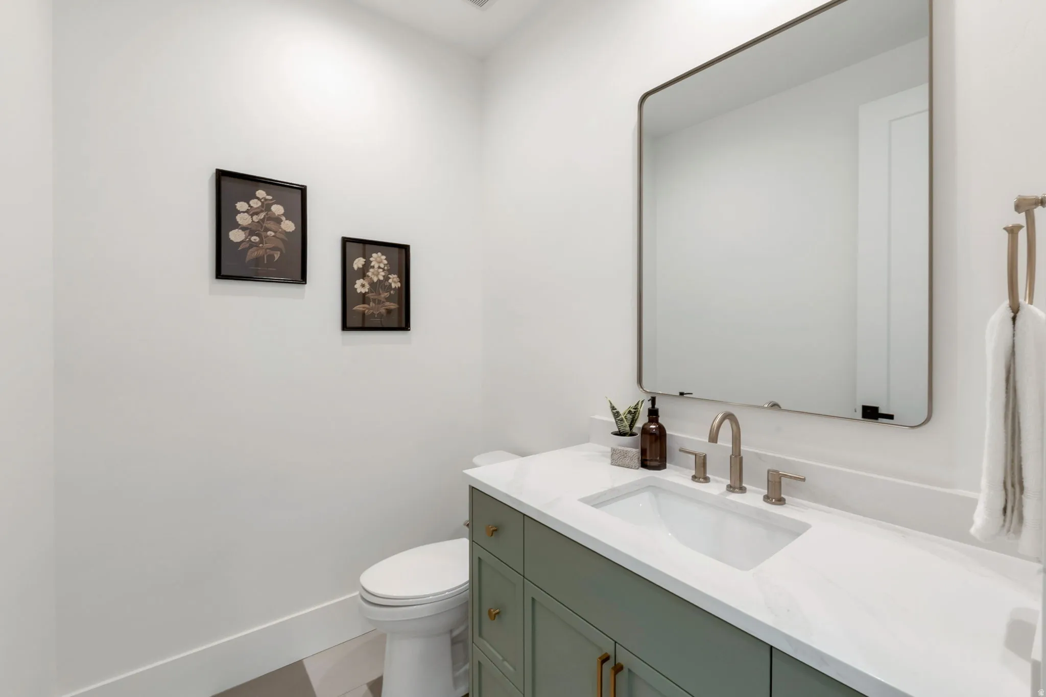 Powder room featuring a sage green vanity with gold hardware, white countertop, undermount sink, and a framed rectangular mirror