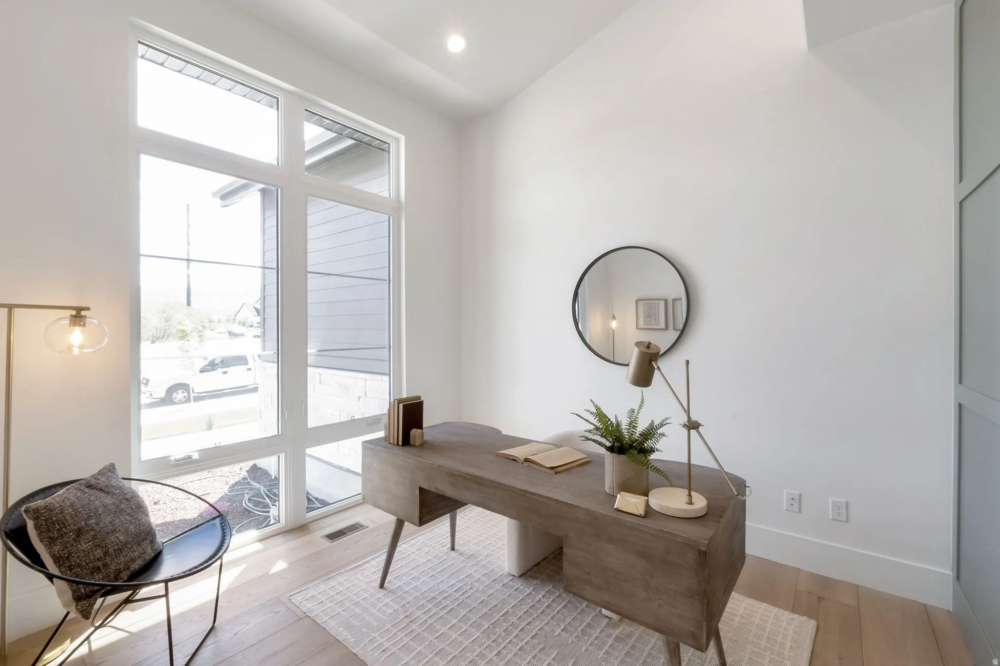 Room featuring expansive multi-pane windows, a vaulted ceiling, light wood-finish flooring, and white painted walls