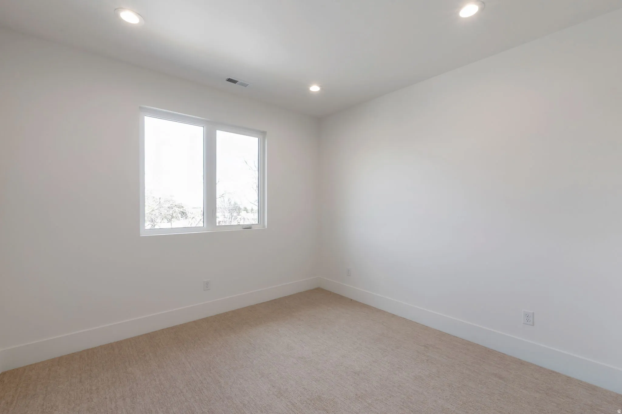 Bright room featuring a large window, recessed lighting, neutral-toned carpeting, white walls, and white baseboards